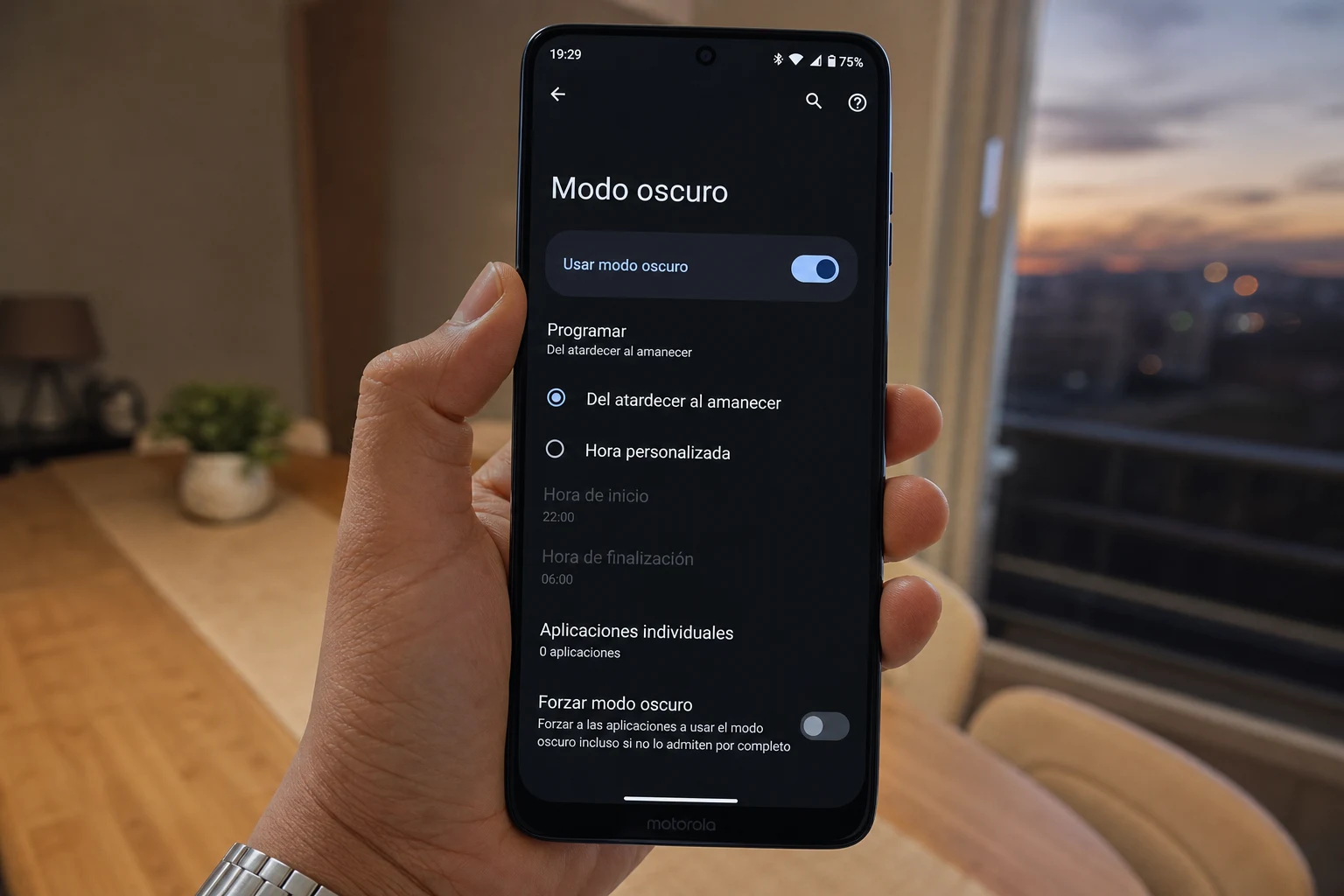 Persona sosteniendo smartphone Motorola con menú de modo oscuro en español