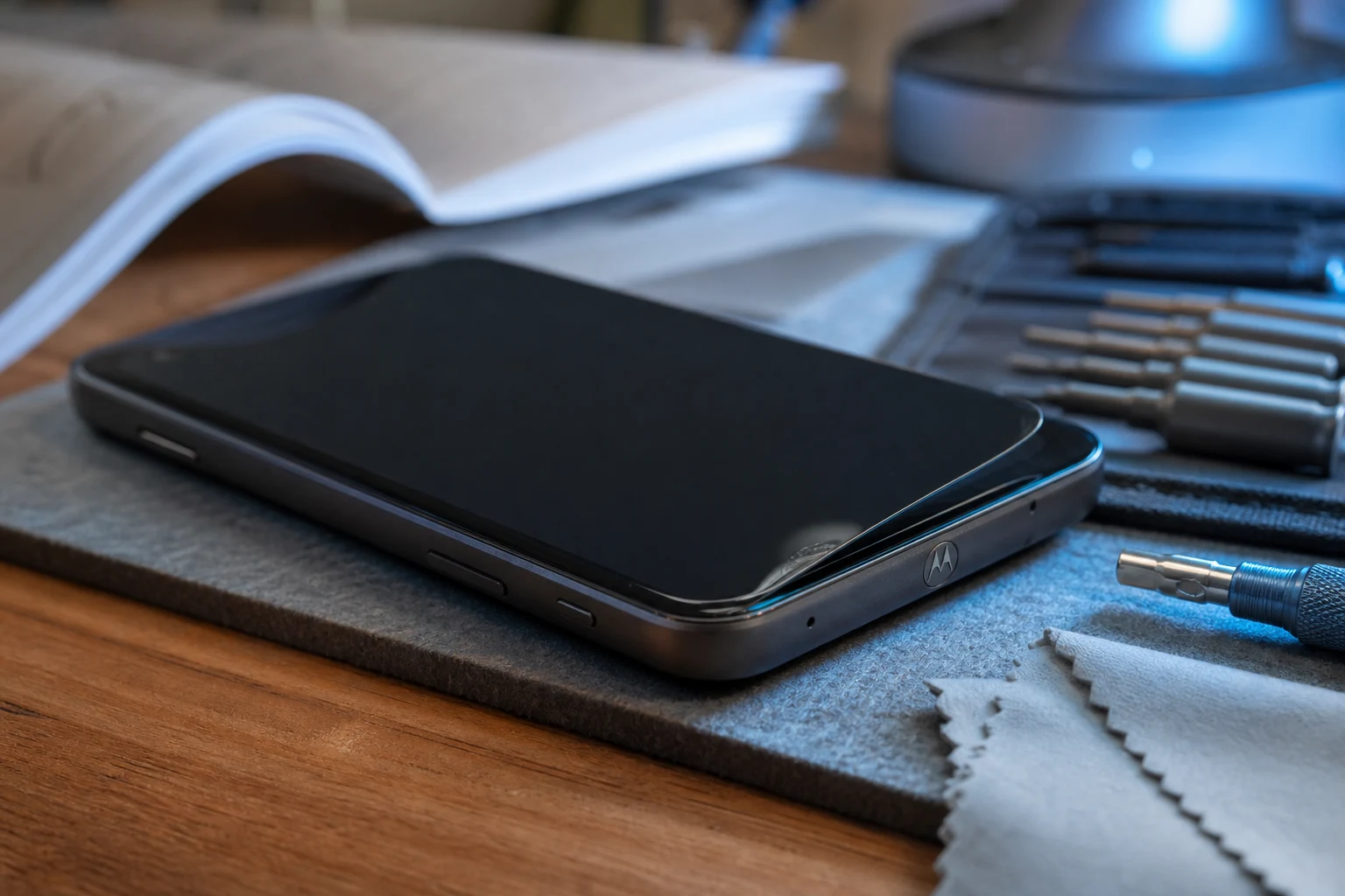Smartphone Motorola con pantalla oscura junto a kit compacto de reparación