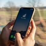 Mano sosteniendo smartphone con señal débil en tren en movimiento