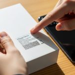 Manos sosteniendo caja de Xiaomi smartphone con etiqueta y logo visibles