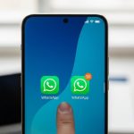 Dedo tocando pantalla de smartphone Xiaomi con dos iconos de WhatsApp