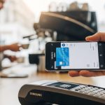 Mano sosteniendo un smartphone Samsung frente a terminal de pago
