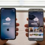 Manos sosteniendo un iPhone y un Samsung en mesa de madera